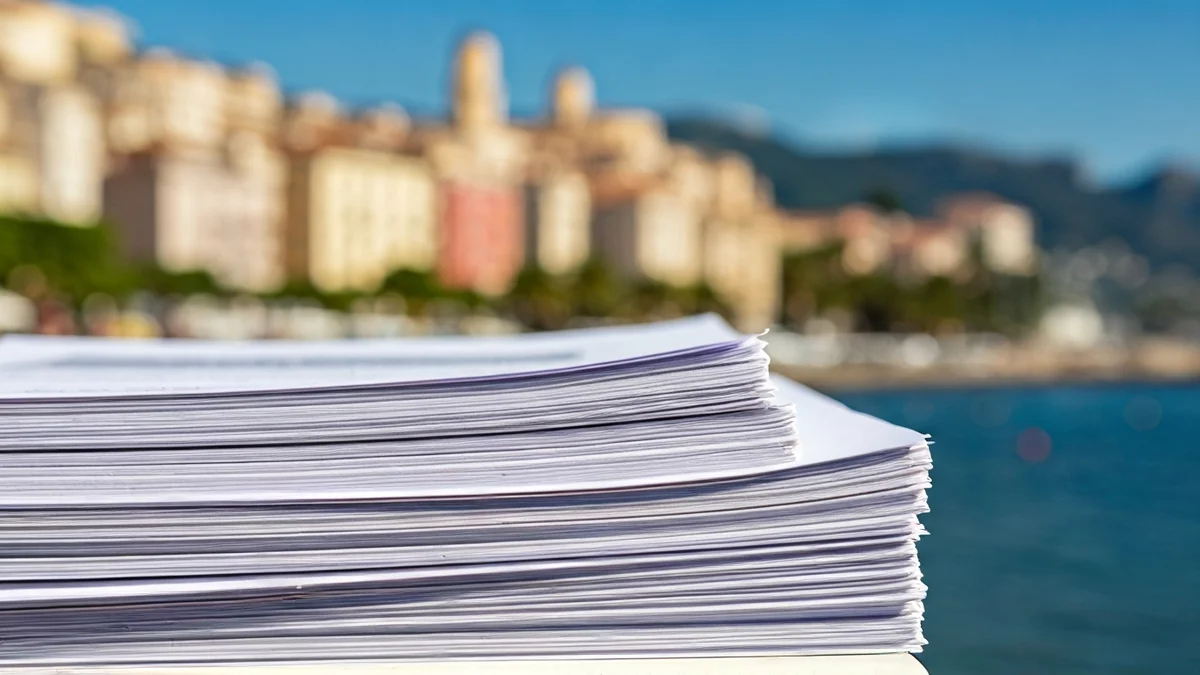 Imagen genérica de documentos legales o avisos de desalojo, con un fondo difuminado de una ciudad costera mediterránea.
