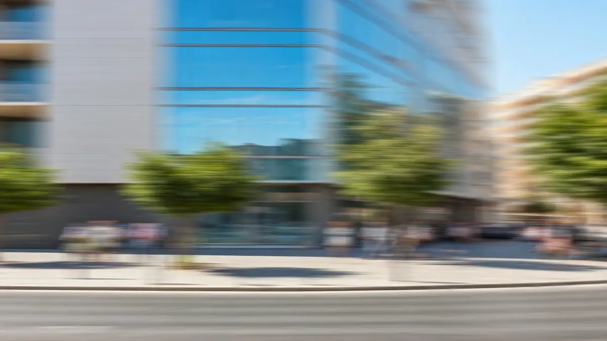 Image of a modern building in a Mediterranean city, with windows reflecting the sky.