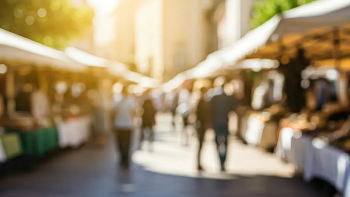Imagen genérica de una feria de comercio local en una plaza mediterránea, con puestos y gente paseando.