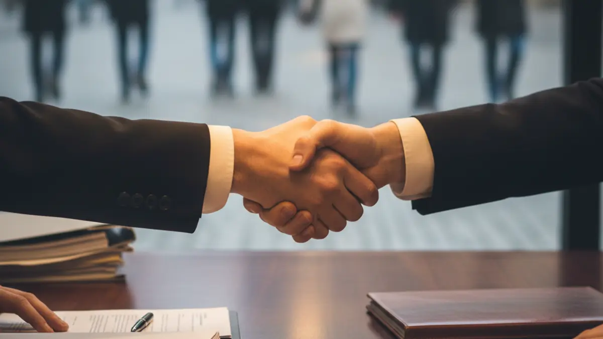 Generic image of two hands shaking in an office setting, symbolizing a business agreement.