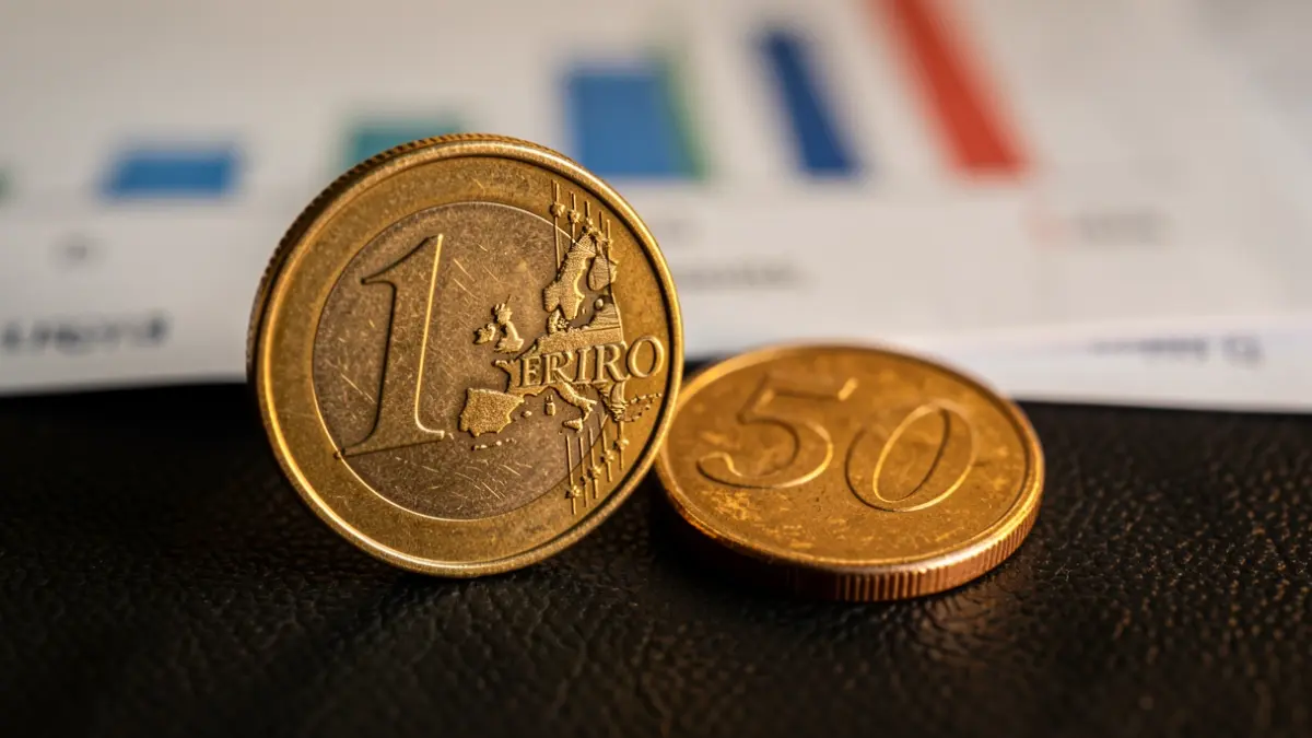 Primer plano de una moneda de euro y una de 50 céntimos sobre fondo oscuro.