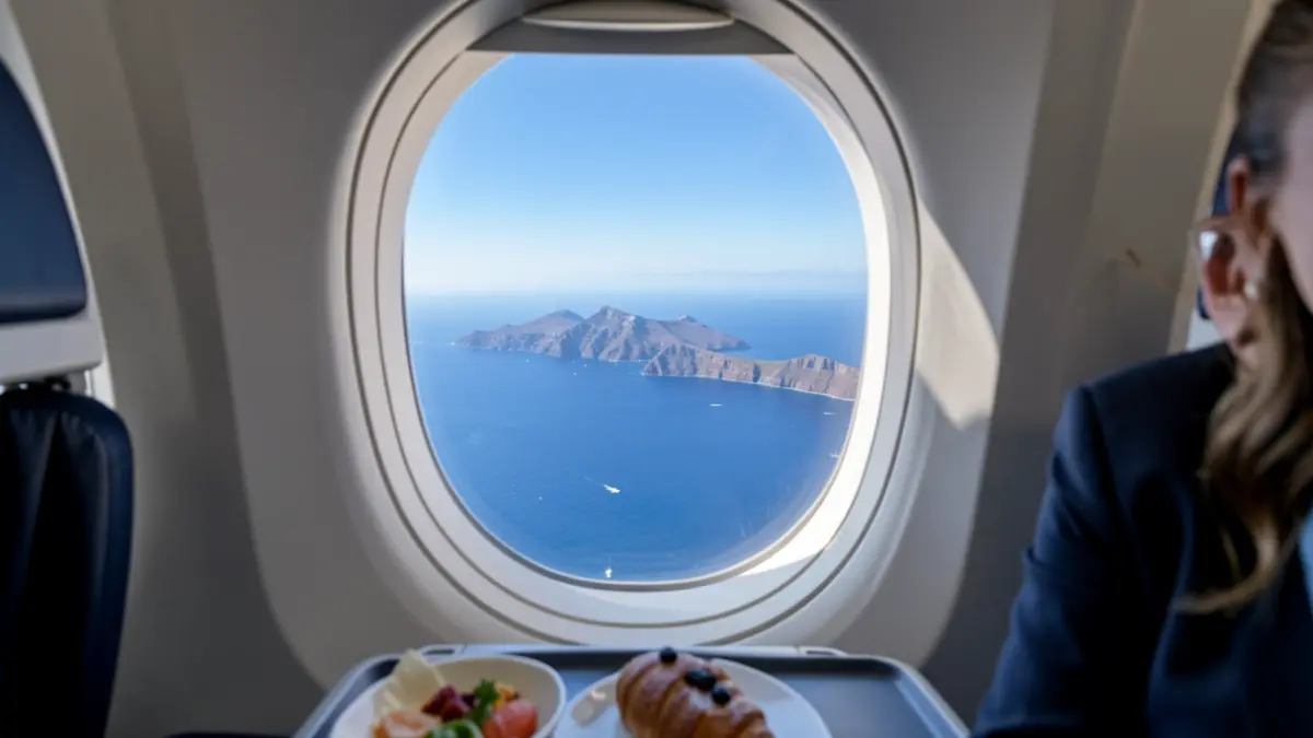 Imagen de una ventana de avión con vista de las Islas Canarias y un aperitivo.