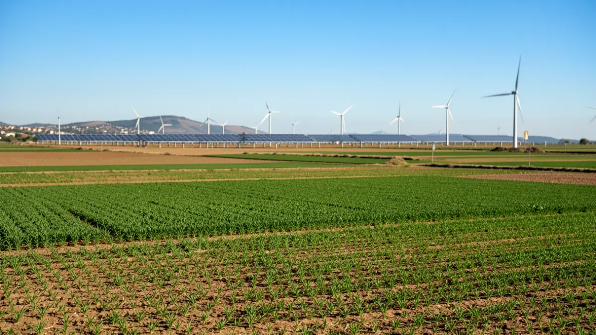 Imagen genérica de campos agrícolas con una instalación fotovoltaica al fondo.