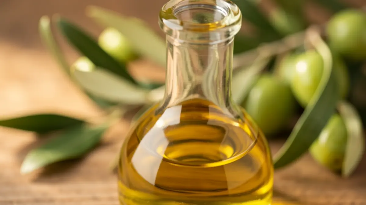Close-up of golden extra virgin olive oil in a bottle.