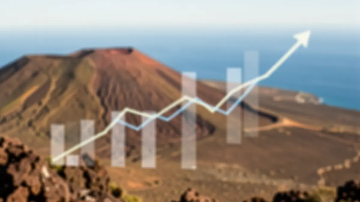 Gráficos económicos abstractos con tendencia descendente sobre un paisaje volcánico de Canarias.