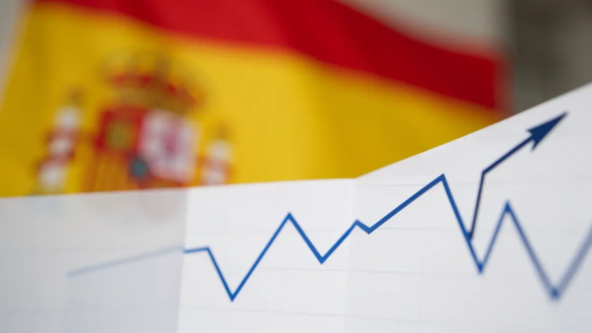 Abstract downward trend graph with a blurred Spanish flag in the background.
