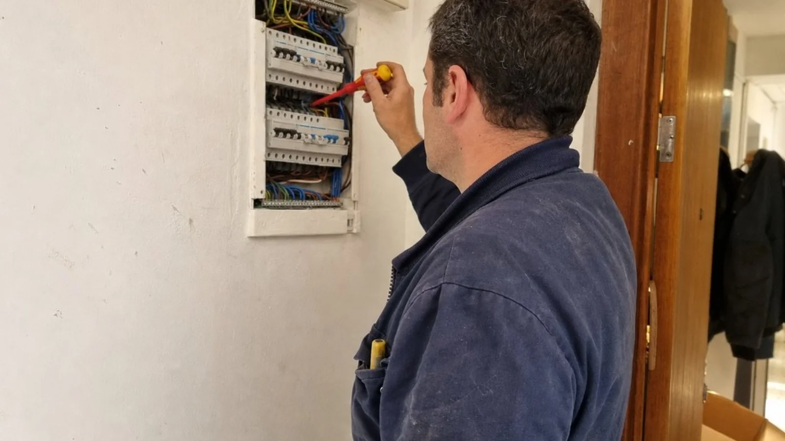 Electricista trabajando en un cuadro eléctrico europeo dentro de una vivienda