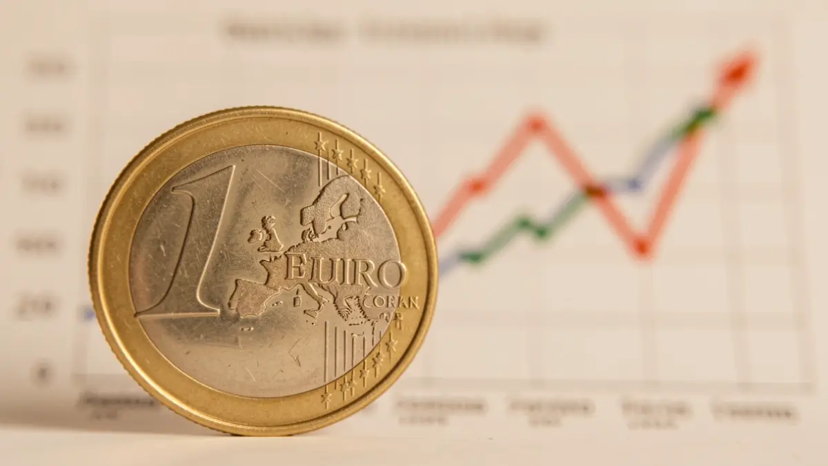 Close-up of a Spanish euro coin with an economic trends graph in the background.