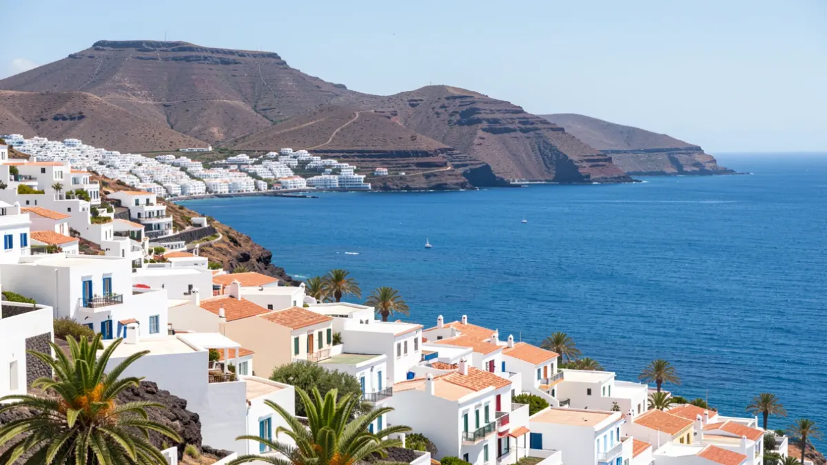 Panoramic view of a coastal municipality in Lanzarote with white architecture and volcanic hills.